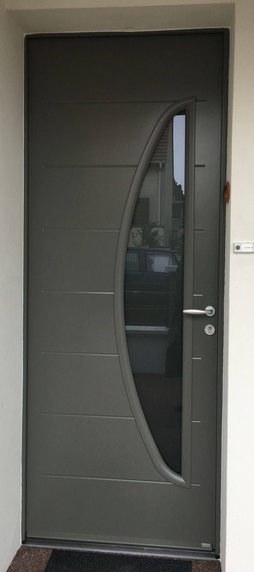 Porte d'entrée grise avec un insert vertical en verre dépoli et une poignée argentée