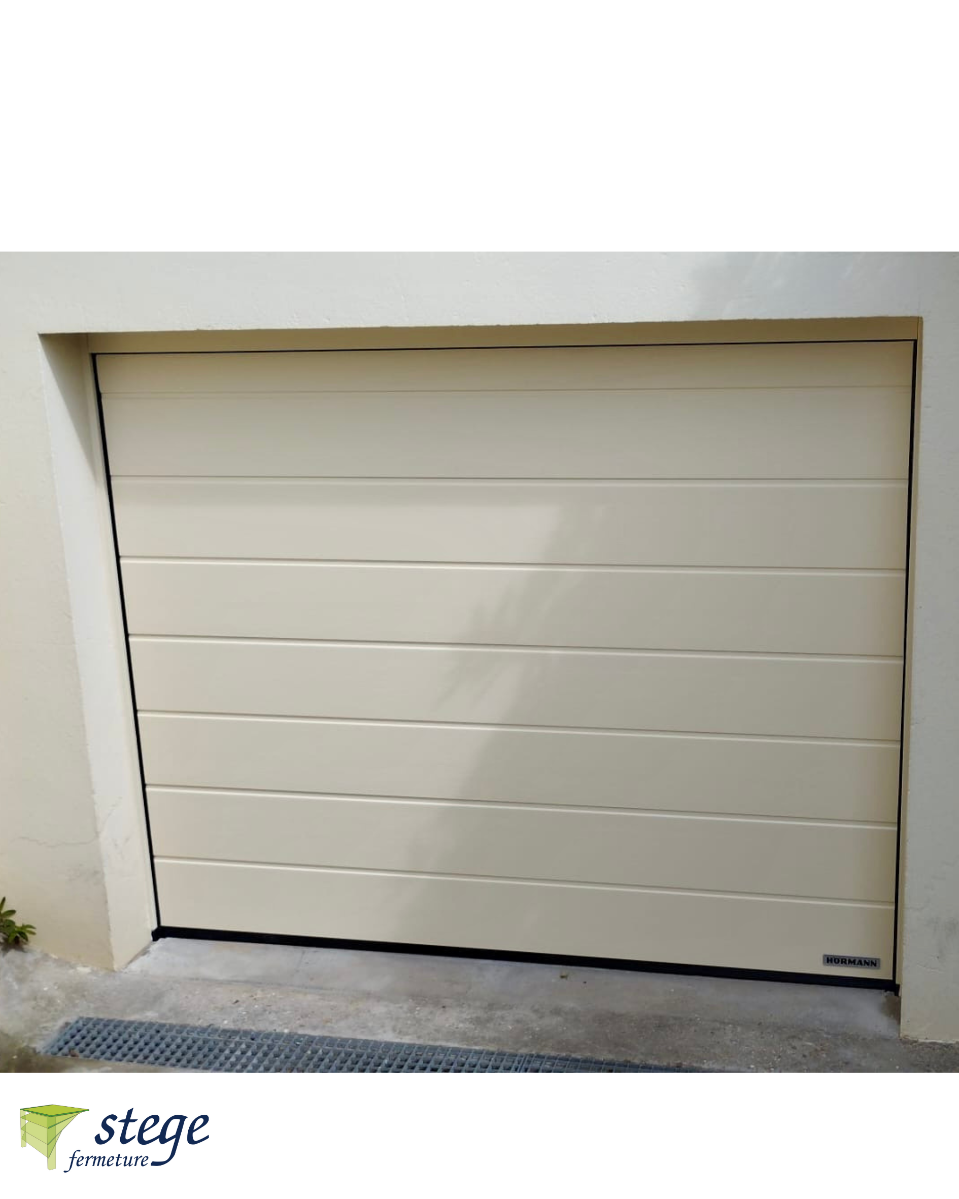 Porte de garage beige fermée sur un mur extérieur blanc avec une allée en béton.