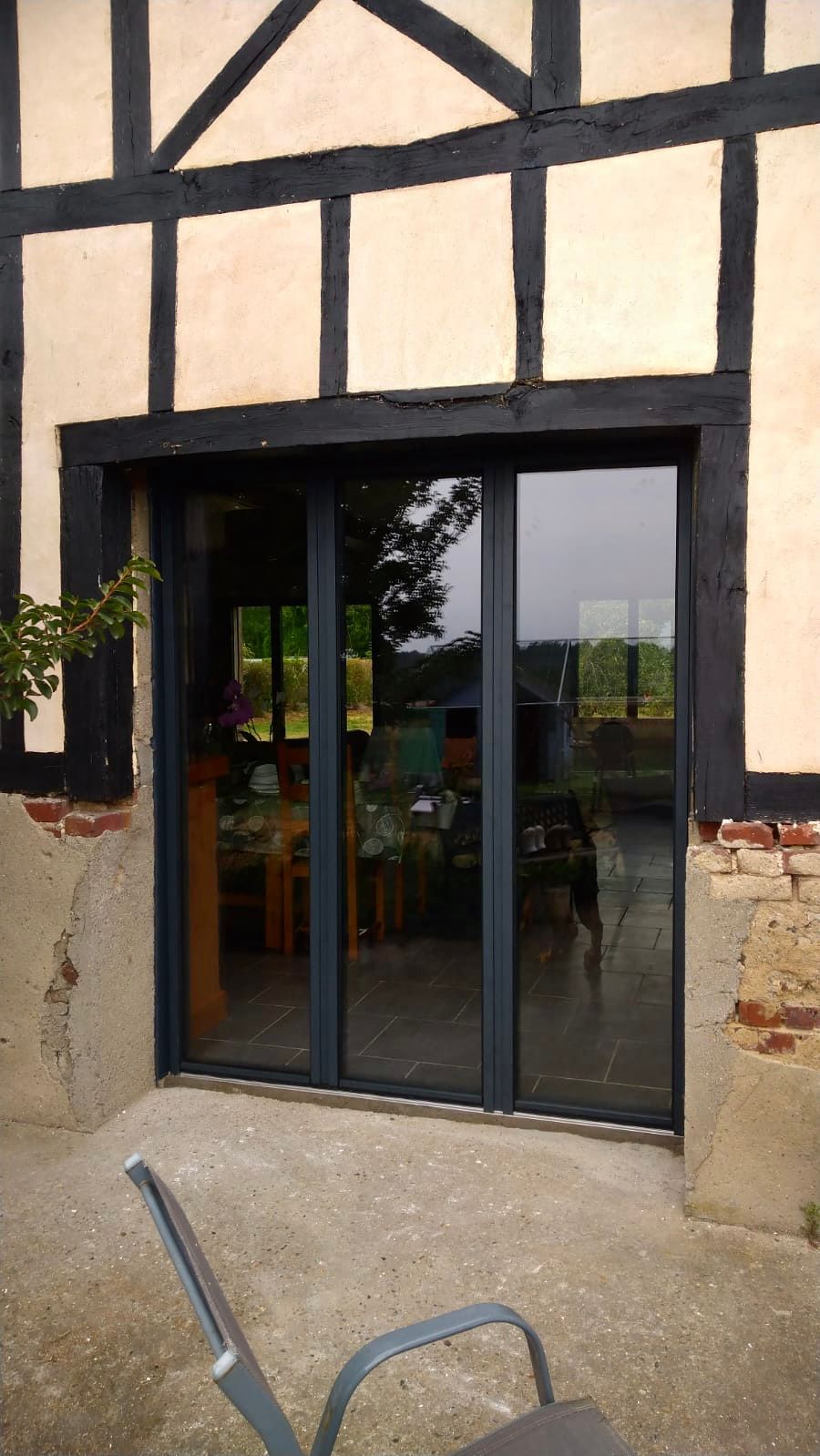Porte vitrée dans un bâtiment à colombages beige, avec une chaise au premier plan.