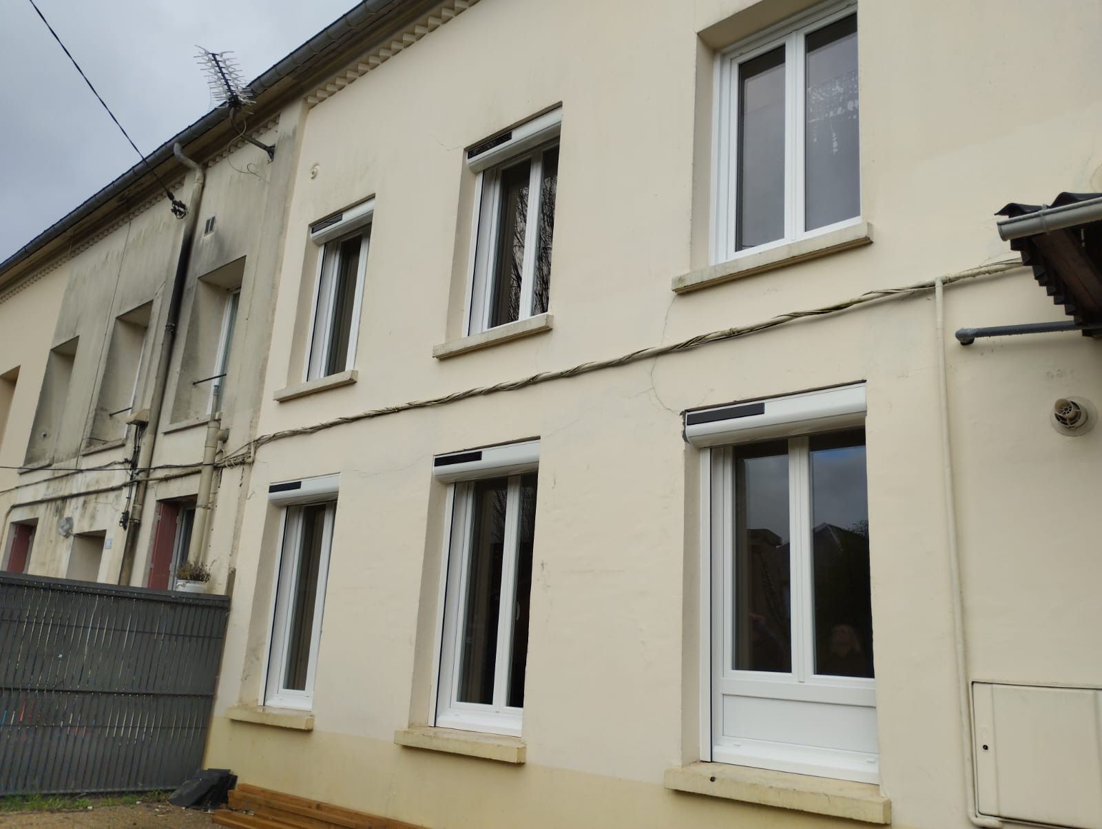 Rangée de maisons résidentielles beiges aux fenêtres blanches et une clôture métallique sur le côté gauche