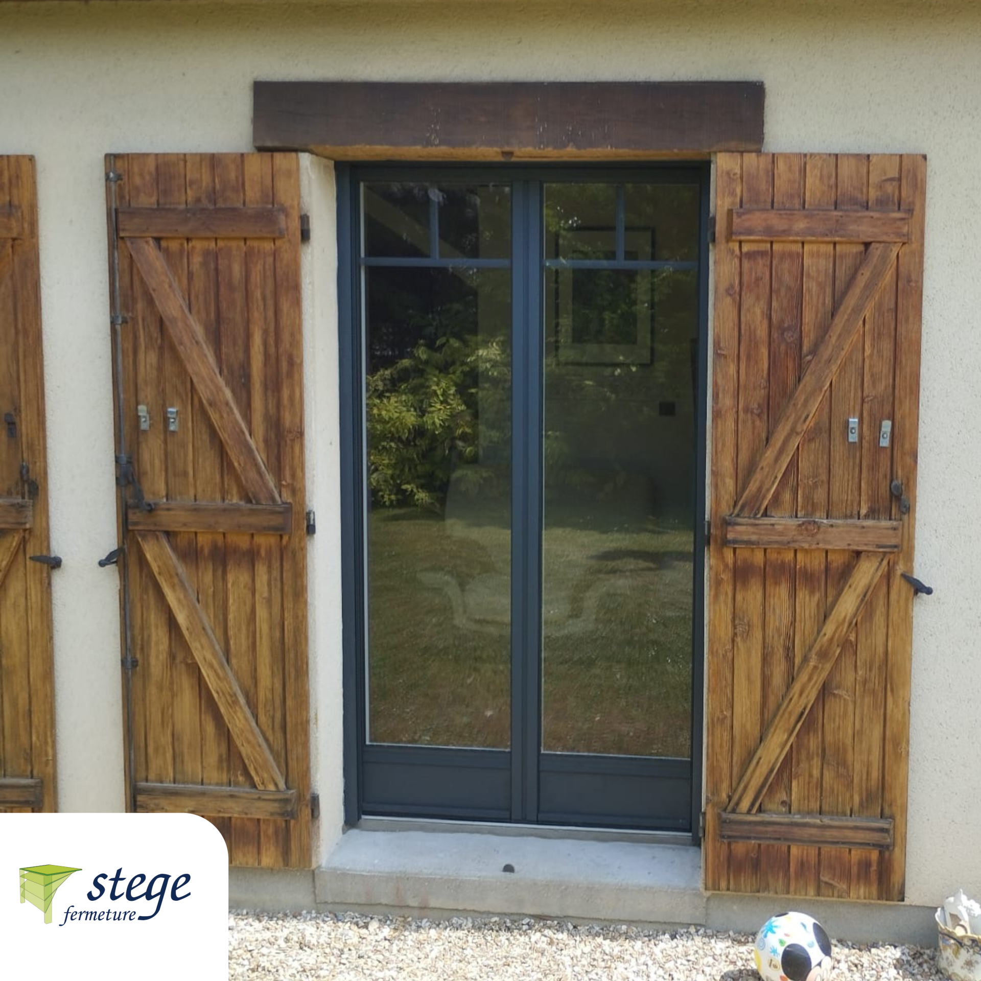 Volets en bois encadrant une double porte vitrée sur la façade beige d'un bâtiment.