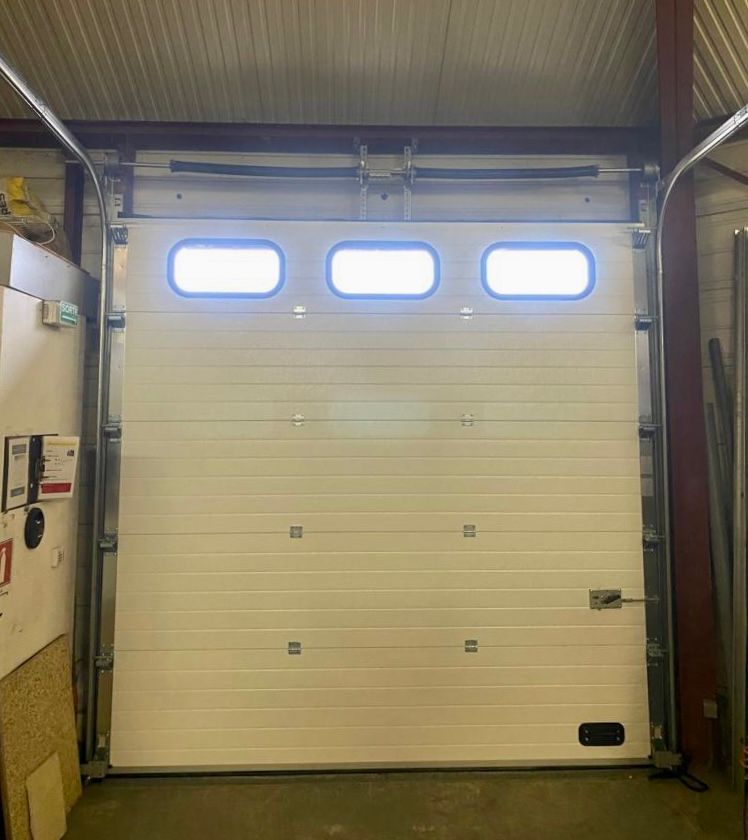 Porte de garage beige fermée avec trois petites fenêtres dans un intérieur de style industriel