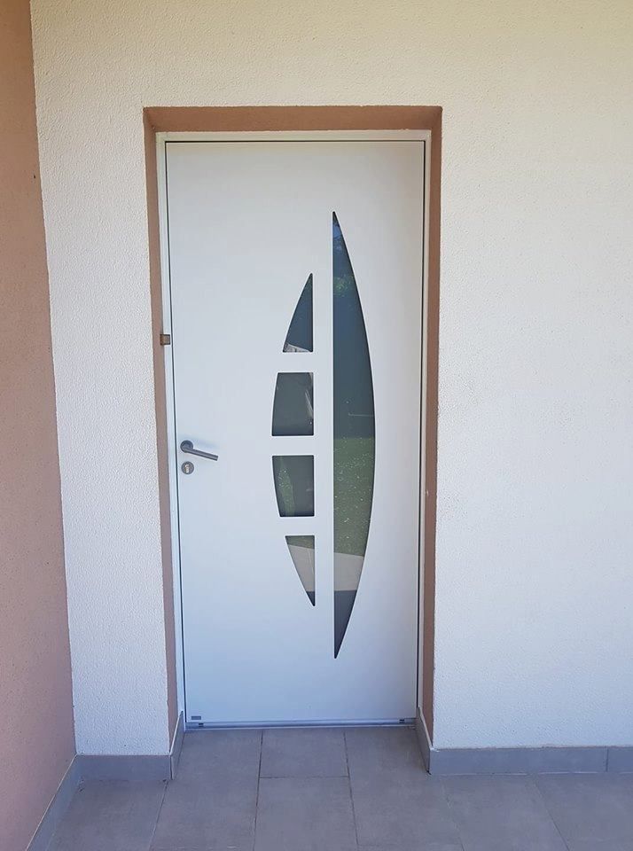 Porte blanche à motif vertical en verre dépoli sur un mur beige, vue depuis un couloir carrelé