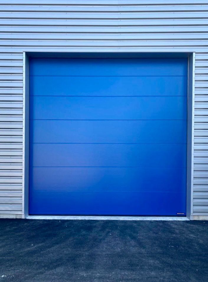 Ensemble de porte de garage industrielle bleue sur un revêtement gris clair.