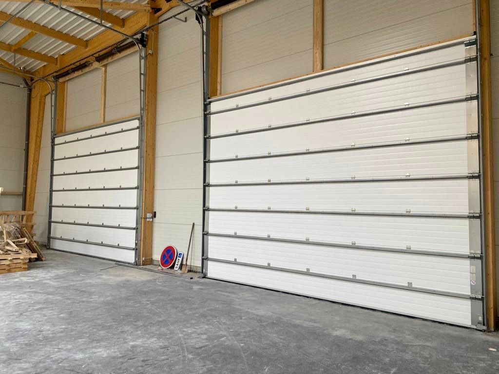 Entrepôt vide avec deux grandes portes sectionnelles blanches et un sol en béton