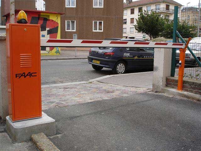 Barrière de parking orange à côté d'une voiture noire garée sur un terrain résidentiel