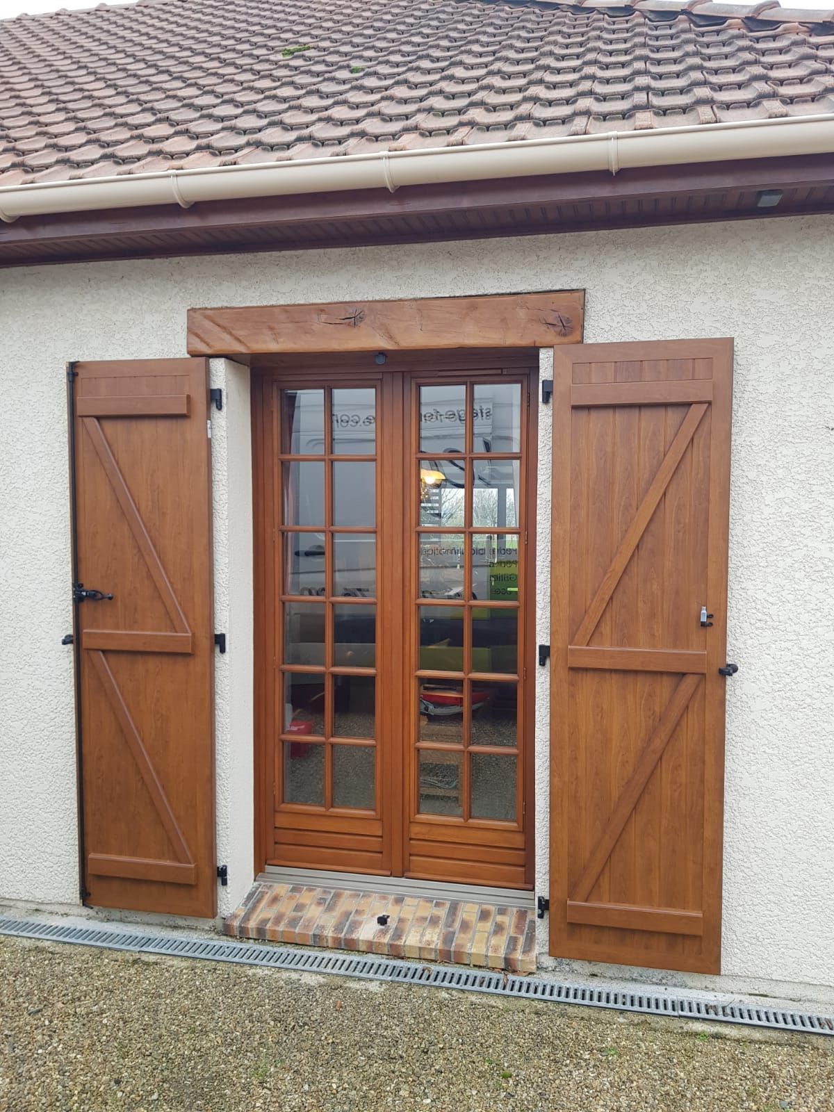 Portes-fenêtres en bois avec volets sur une façade de maison en stuc