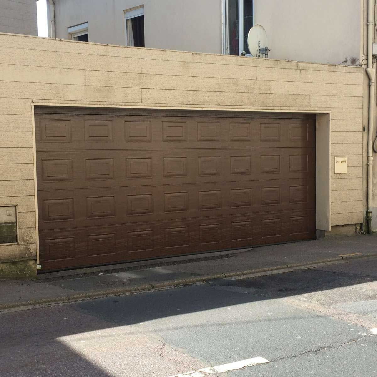 Porte de garage marron fermée sur un bâtiment beige en bordure de rue