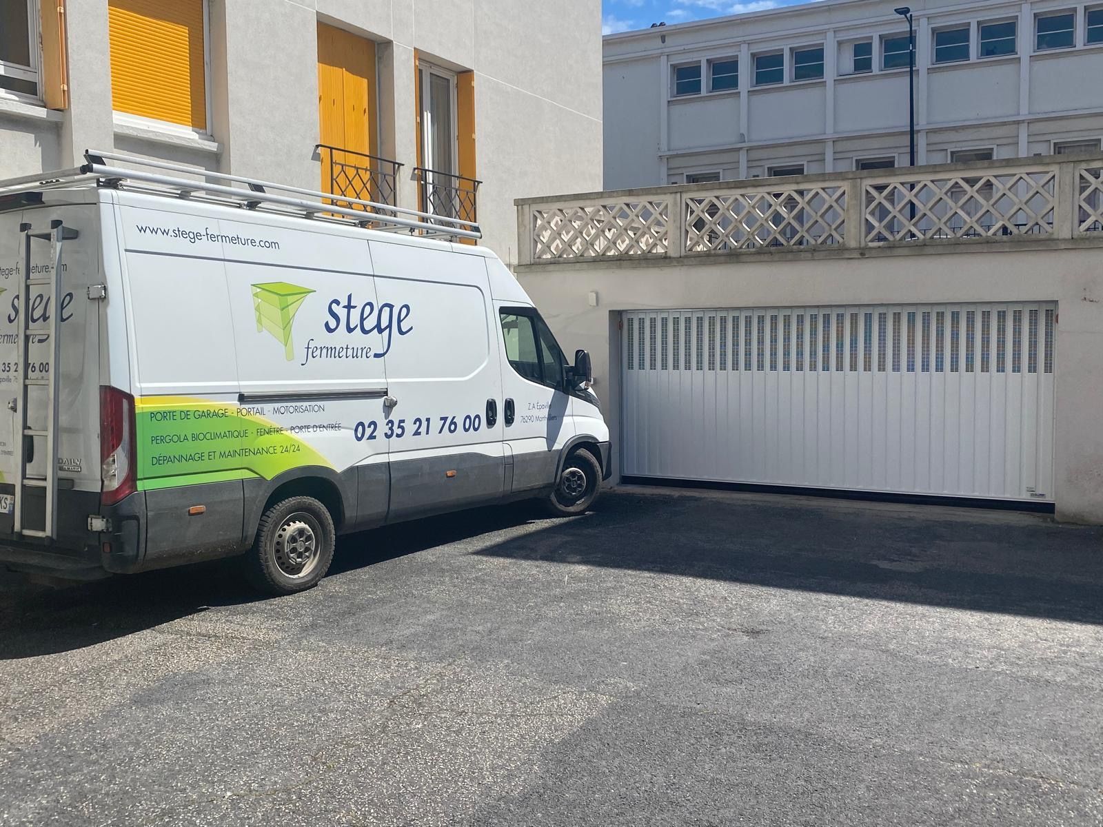 Camionnette de livraison White Stage garée à côté d'un bâtiment et d'une porte de garage dans une cour pavée.