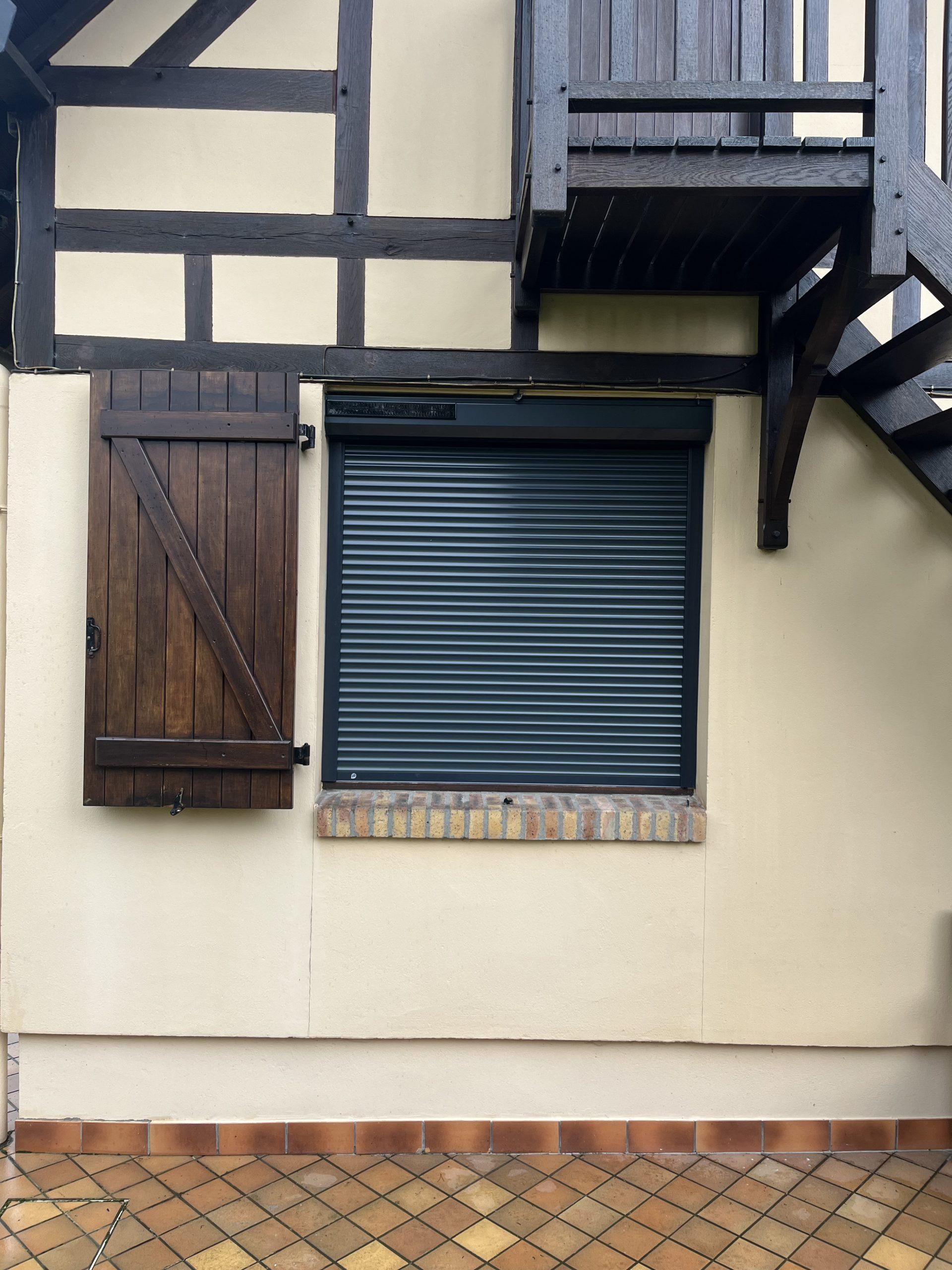 Façade d'un bâtiment à colombages avec volet en bois et store bleu fermé