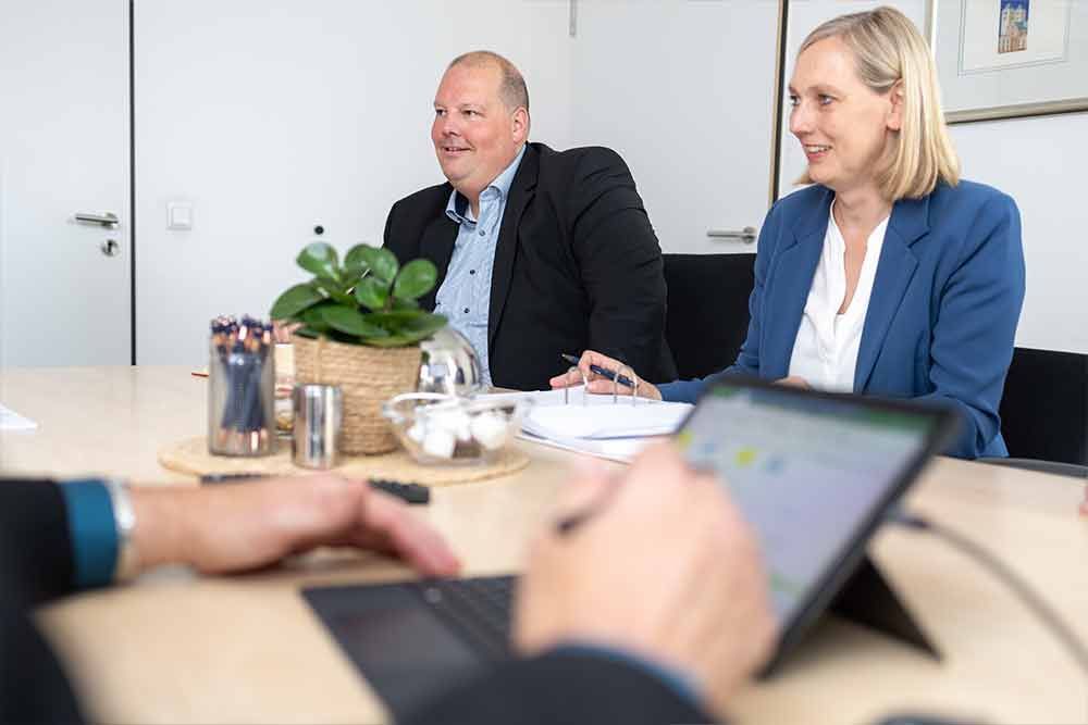 Ein Mann und eine Frau sitzen mit einem Laptop an einem Tisch.
