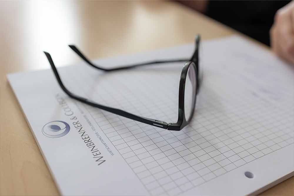 Eine Brille liegt auf einem Stück Papier.