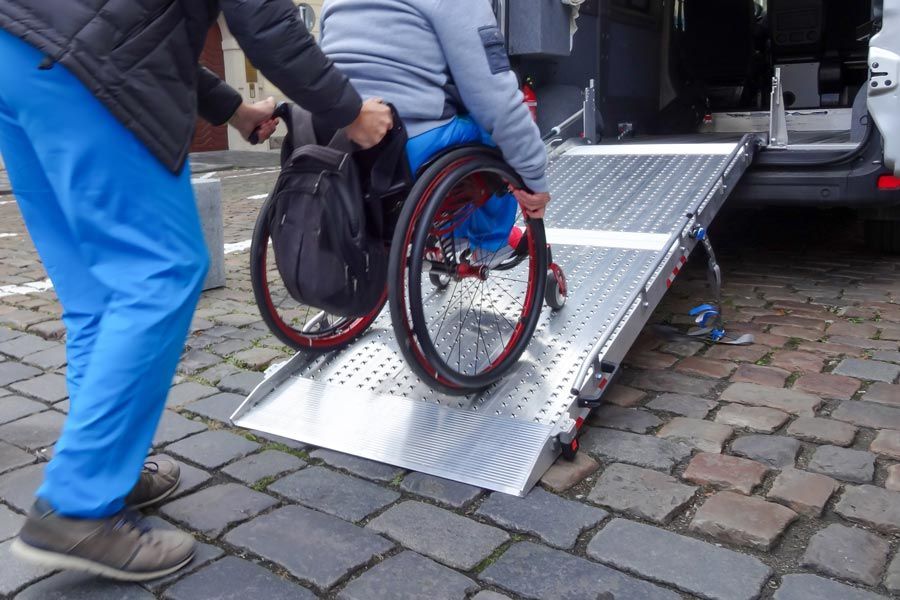 Une personne handicapée qui monte dans une ambulance grâce à une passerelle