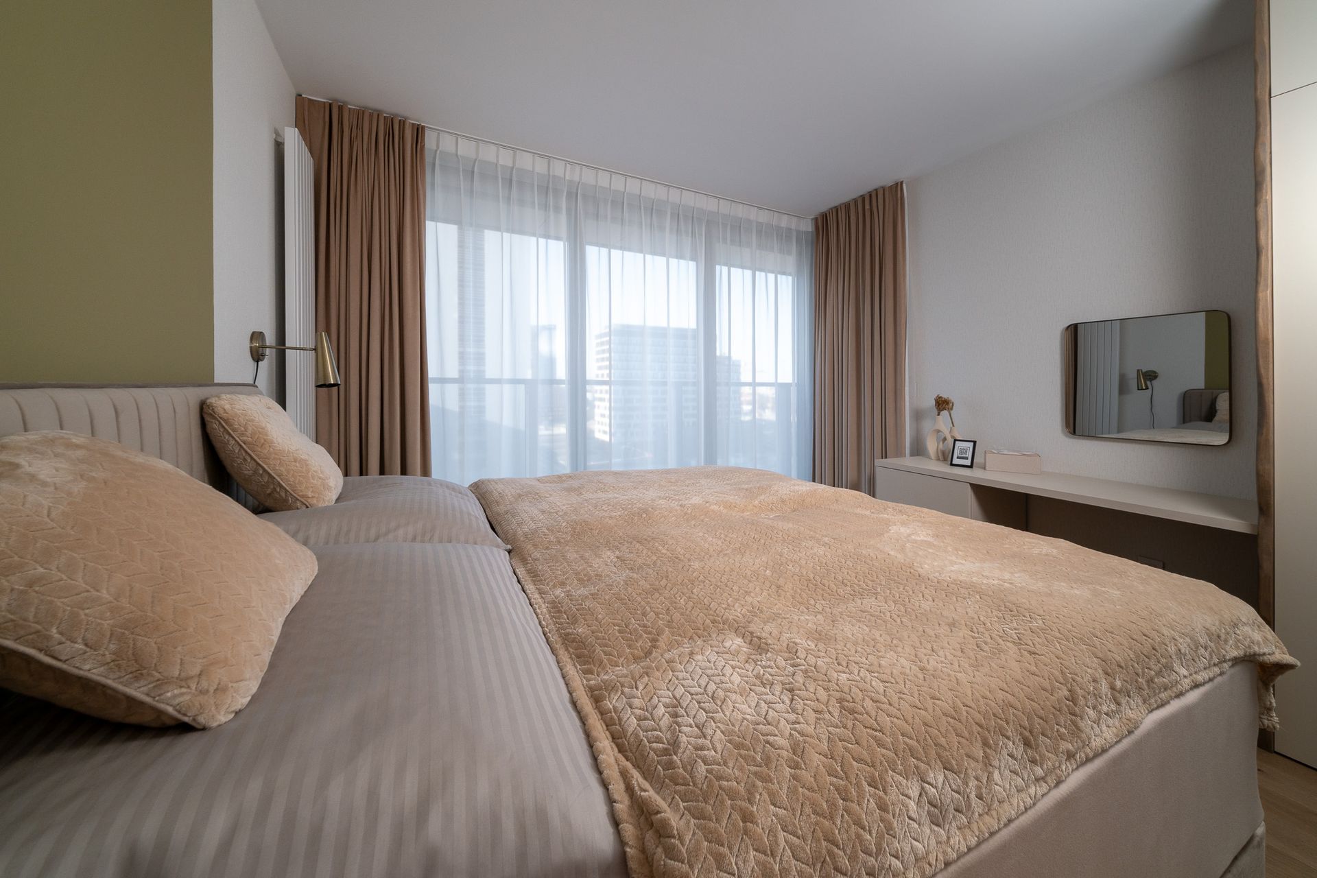 Bedroom with a bed, beige bedding, pillows, curtains, and a window.
