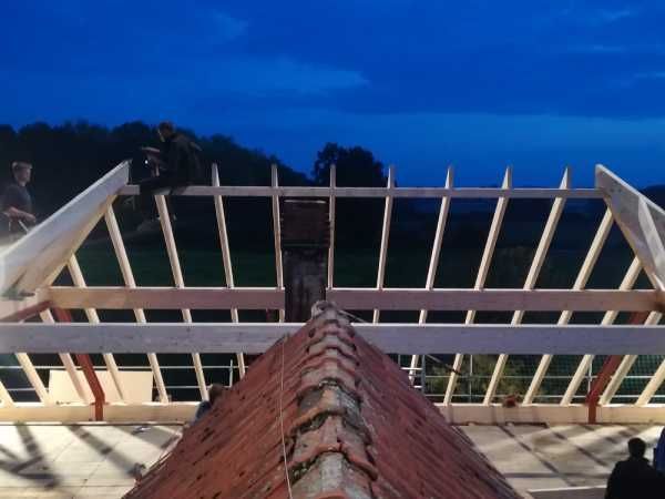 Blick vom Dach eines Hauses auf einen Rohbau aus Holz