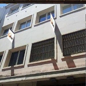 Un edificio con muchas ventanas y una bandera en el costado.