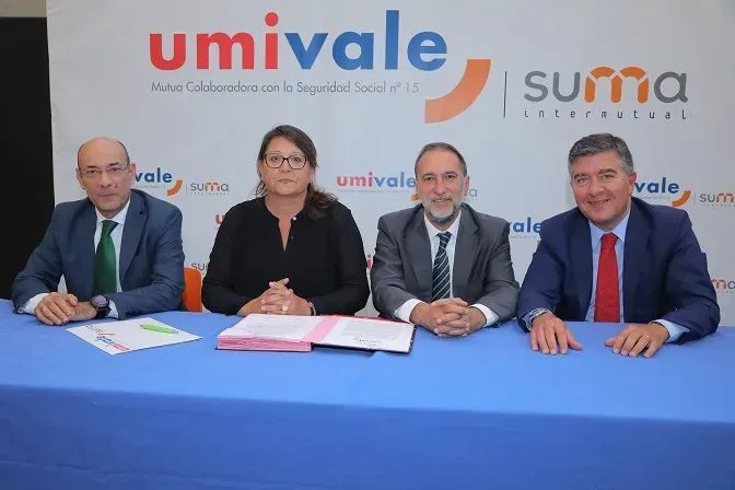 Un grupo de personas está sentado en una mesa frente a un cartel que dice Umivale.