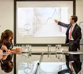 Un hombre está dando una presentación a un grupo de personas en una sala de conferencias.