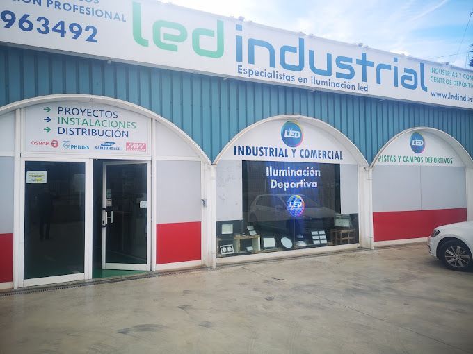 Un coche blanco está aparcado delante de un edificio que dice 