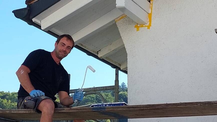 Sammlung antiker Werkzeuge, darunter Hämmer, eine Axt, Zangen und Handschuhe, auf einer Holzoberfläche.