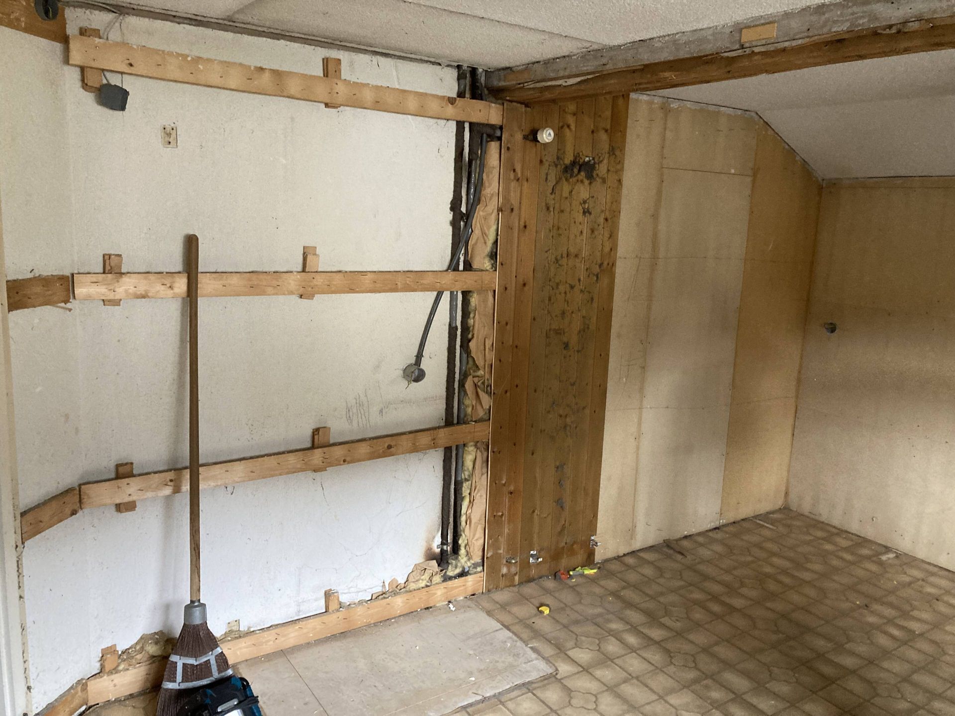 Innenansicht: Wände werden renoviert; freiliegende Holzbalken, Rohrleitungen und beschädigte Verkleidung.