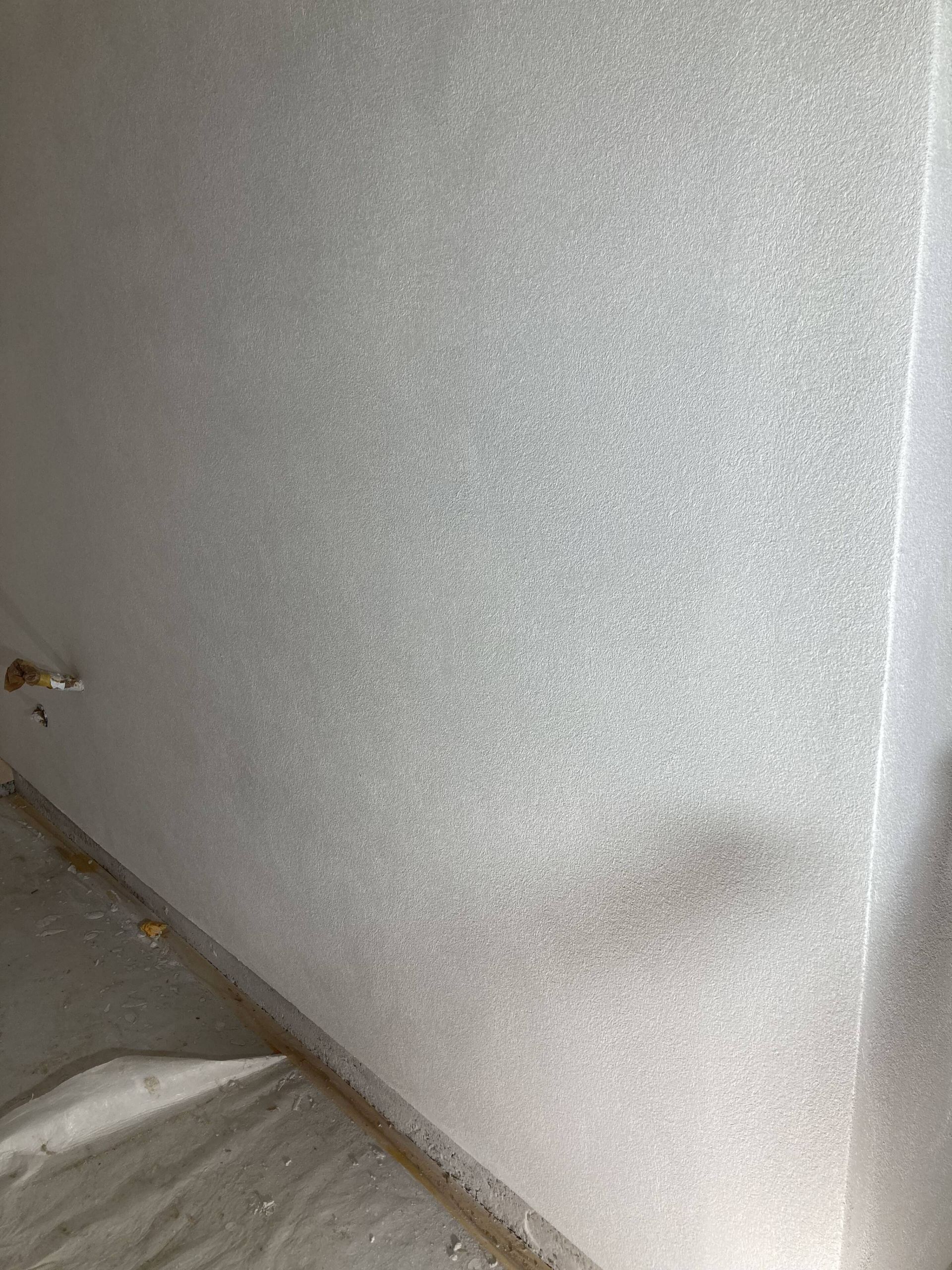 Weiße Wand mit gesprenkelter Textur.