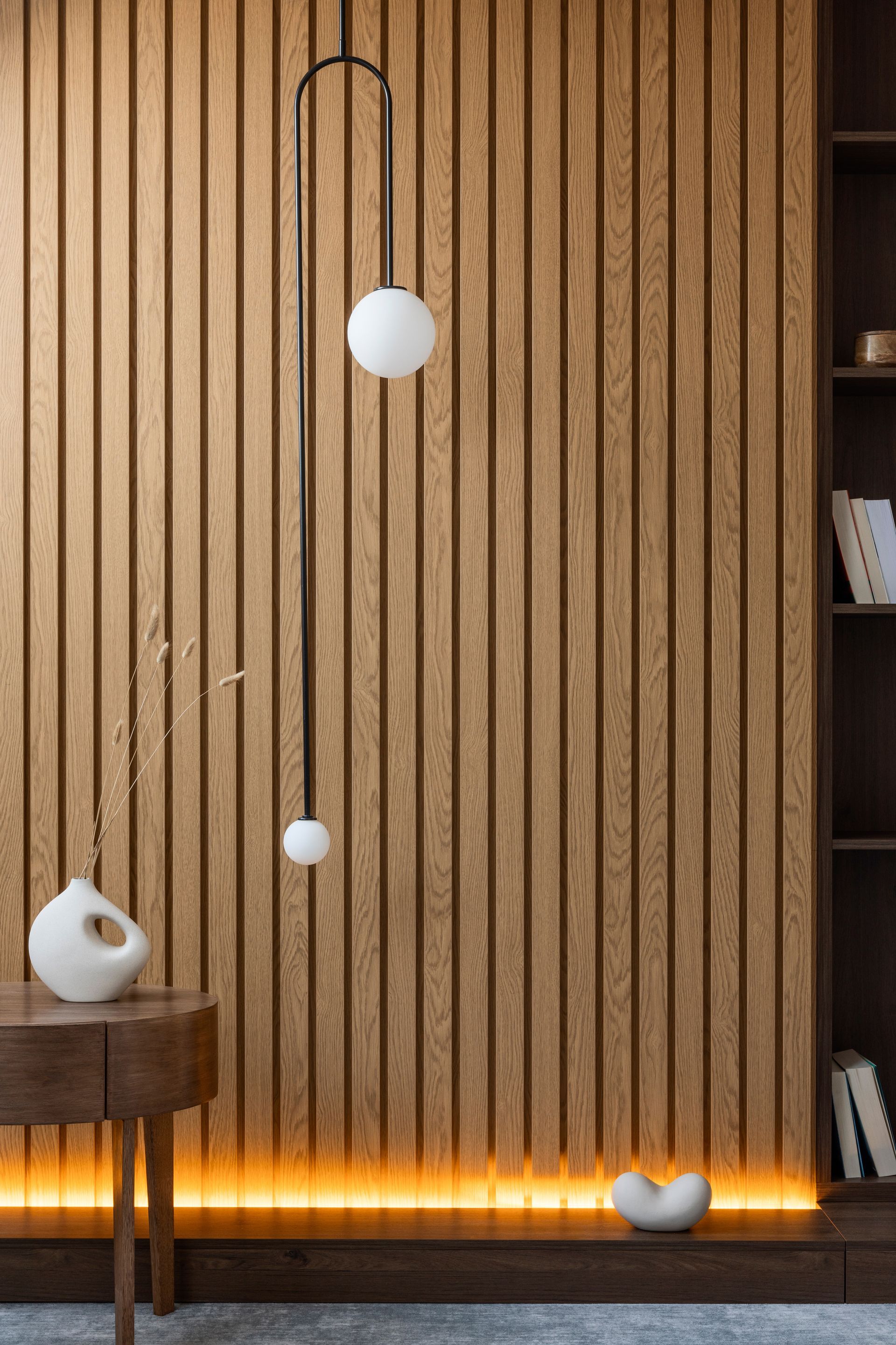 Mur lambrissé en bois avec un luminaire moderne et une décoration minimaliste.