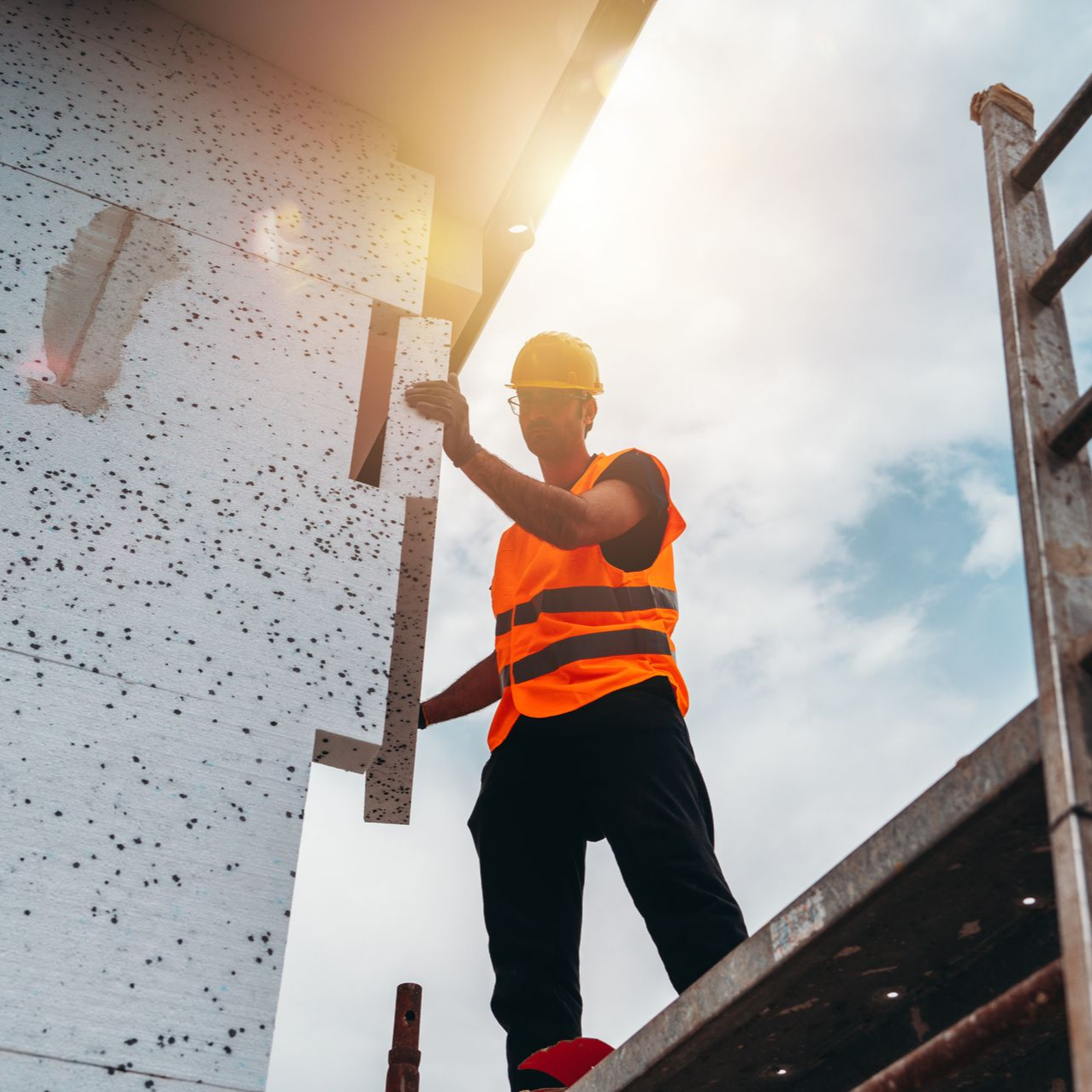 Ouvrier du bâtiment installant de l'isolant sur la façade d'un bâtiment.