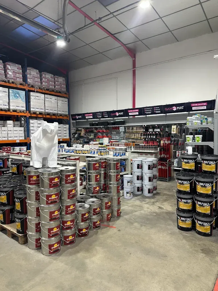 Intérieur du magasin GAMMAT, avec des pots de peinture empilés sur des palettes.