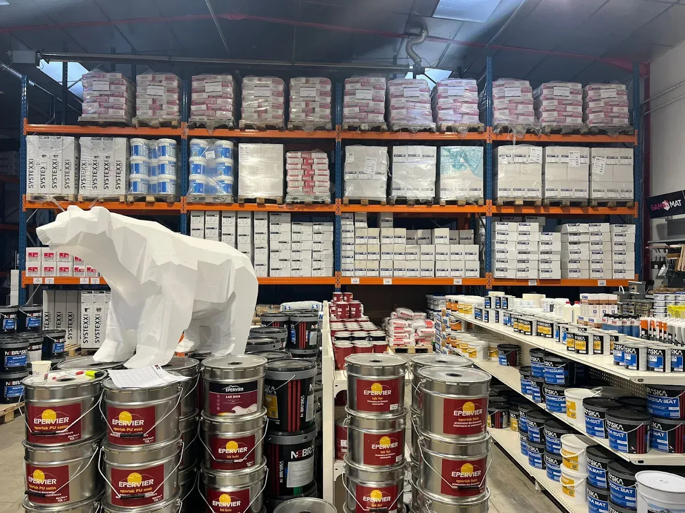 Intérieur du magasin avec des pots de peinture et des étagères remplies de matériaux de construction.