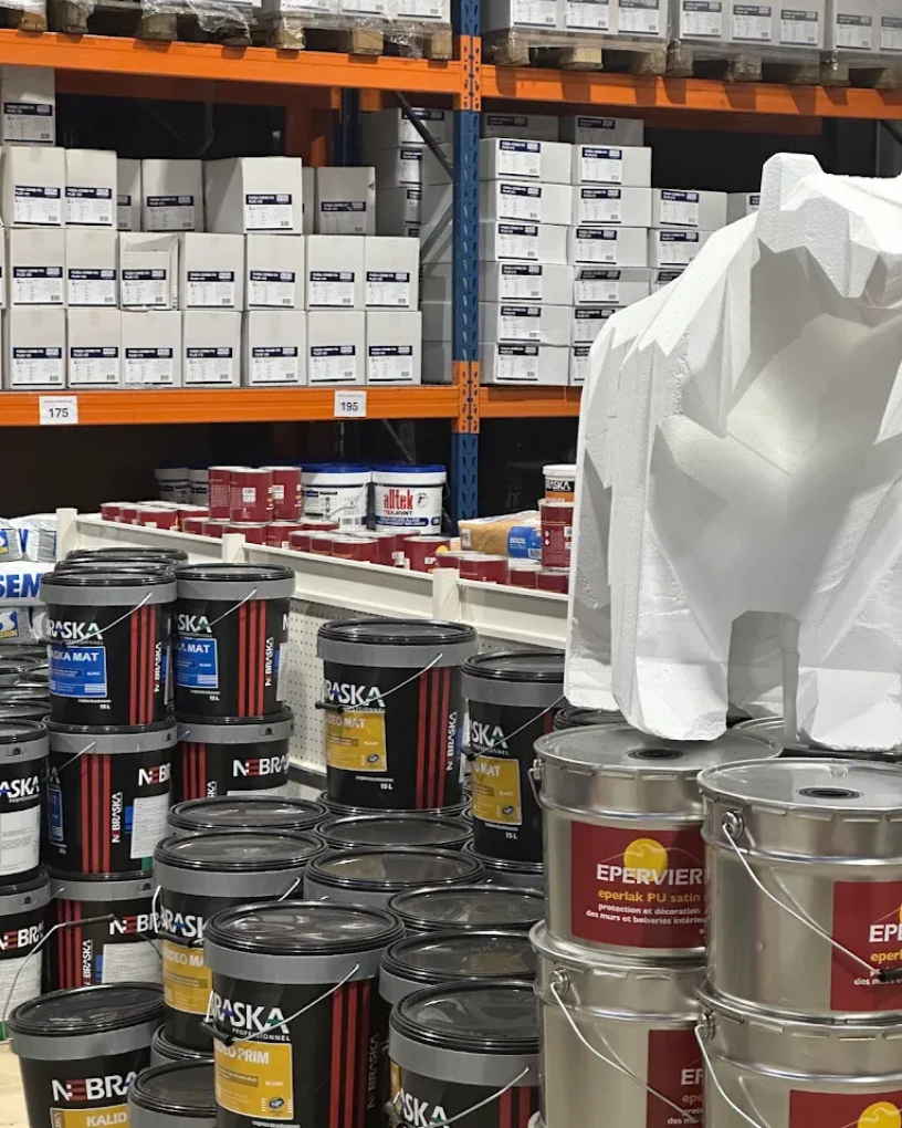 Des étagères remplies de seaux et de boîtes de peinture dans le magasin.