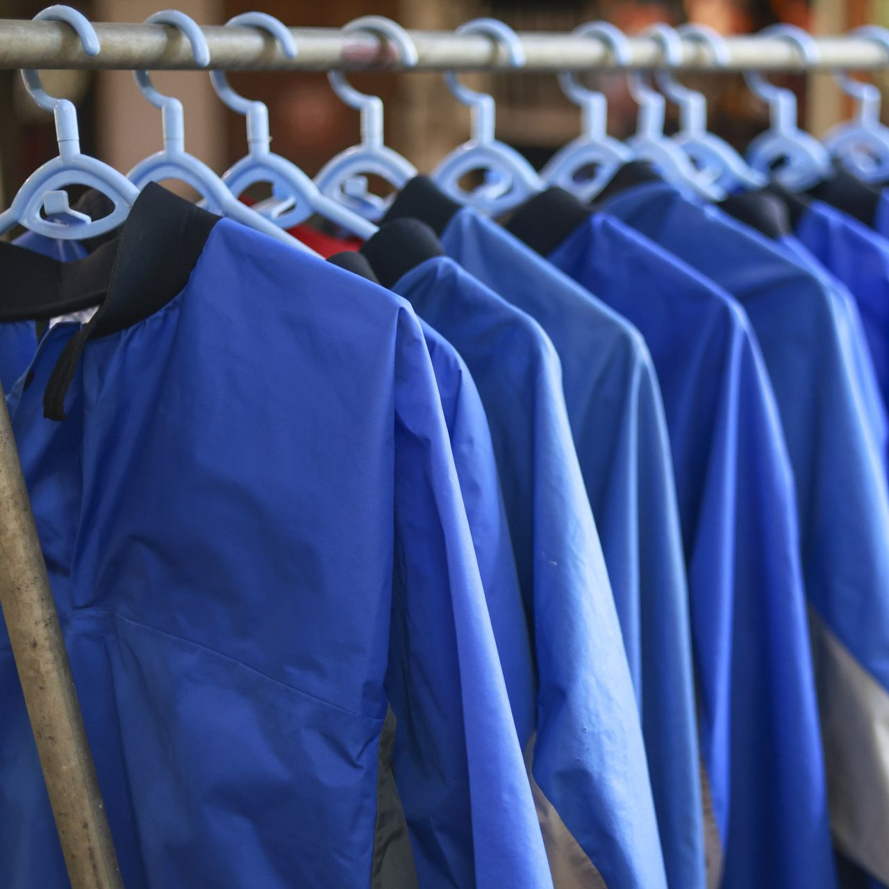 Des vestes bleues suspendues à un portant, chacune avec un col noir.