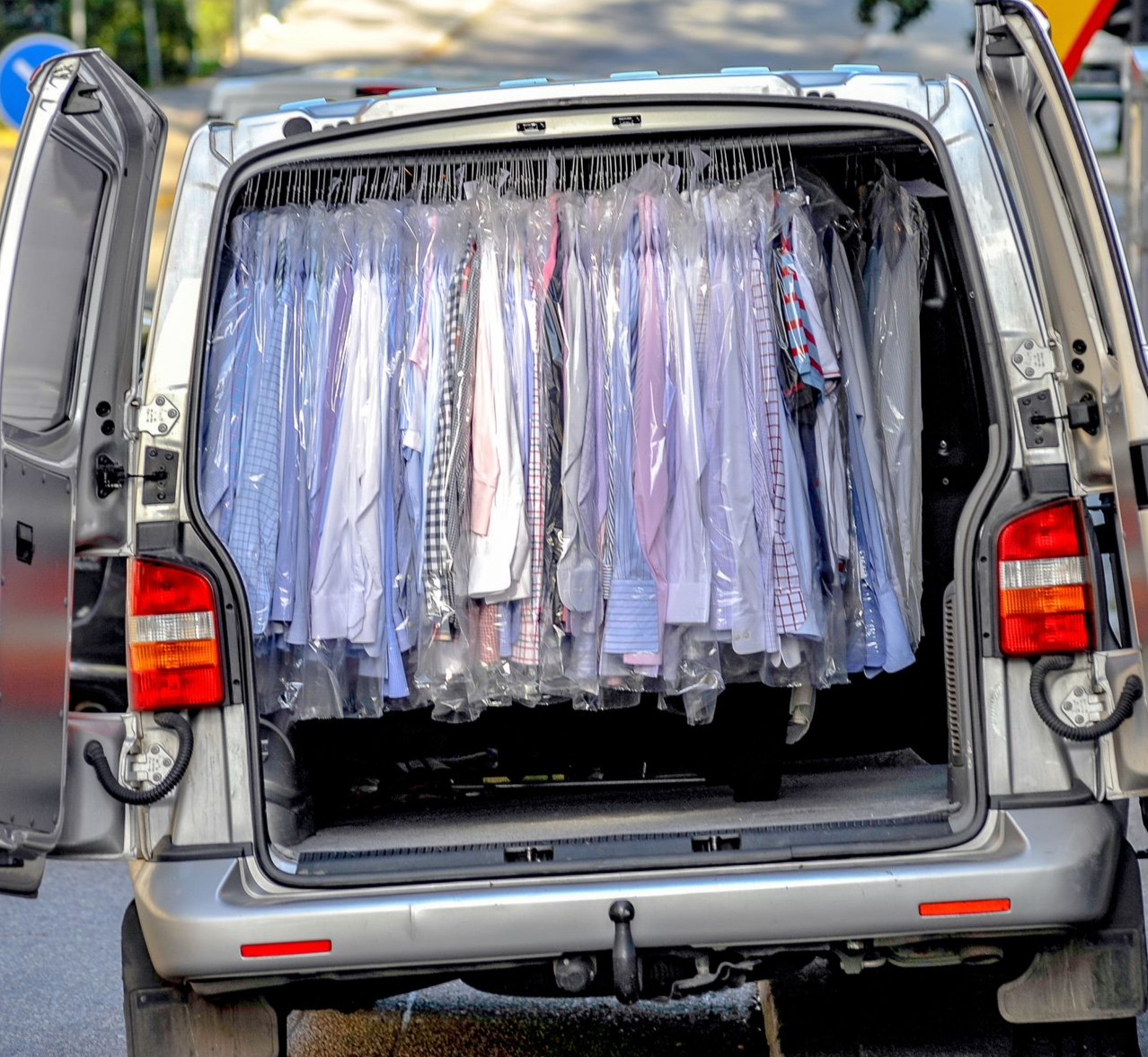 L'arrière d'une camionnette rempli de chemises suspendues et emballées sous film transparent.