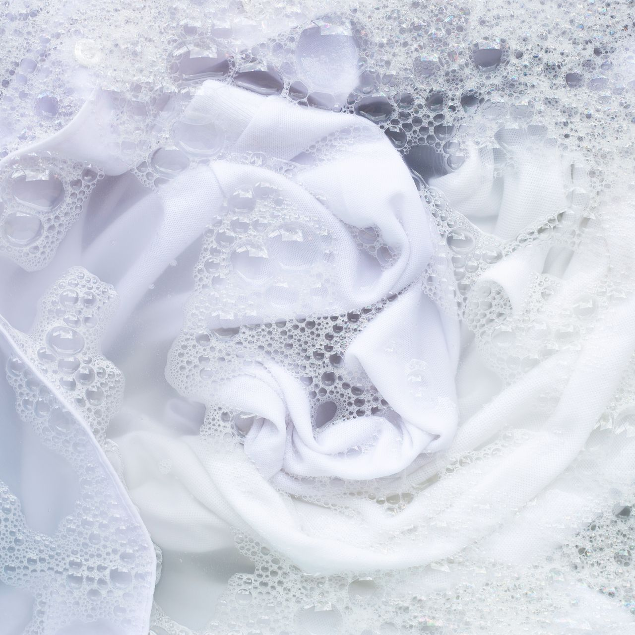 Tissu blanc immergé dans de l'eau savonneuse.