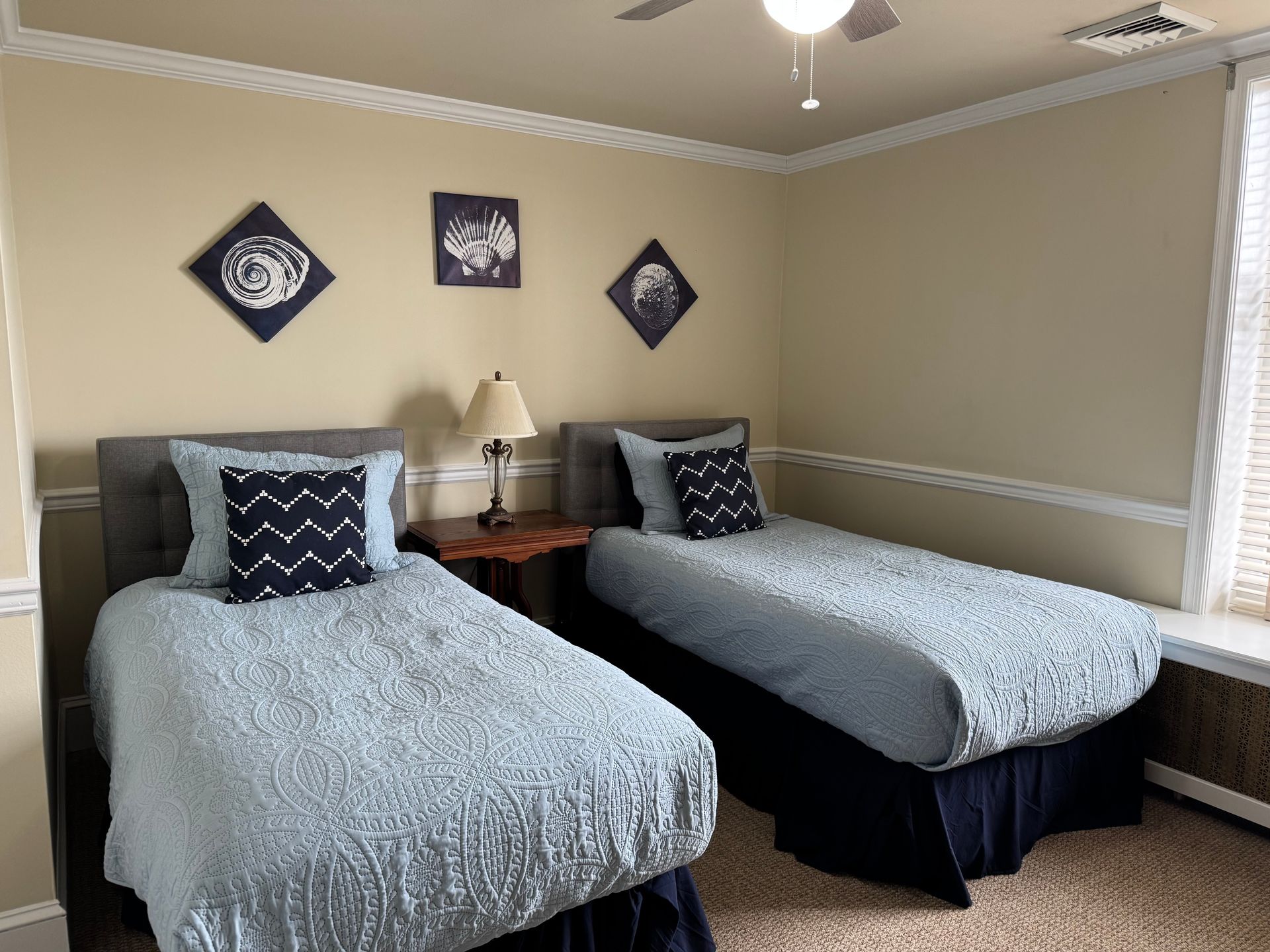 A bedroom with two twin beds and a ceiling fan.