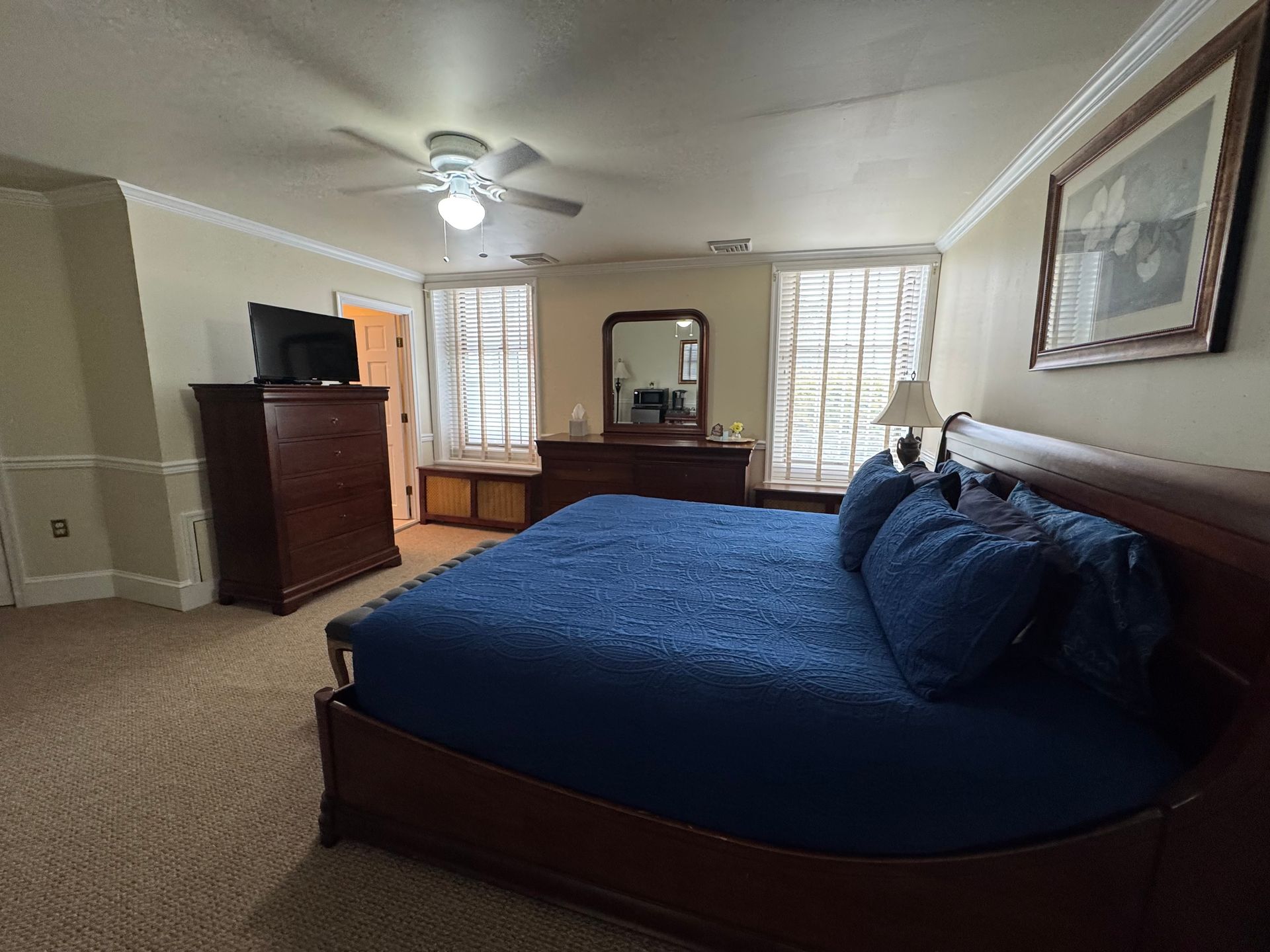 A bedroom with a king size bed , dresser , mirror and television.
