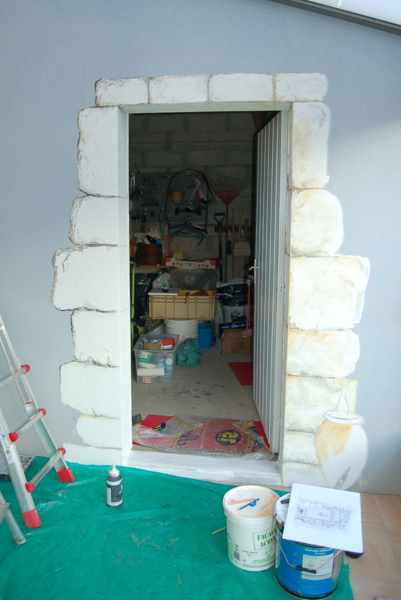 Une échelle est posée à côté d'un seau de peinture devant une porte.