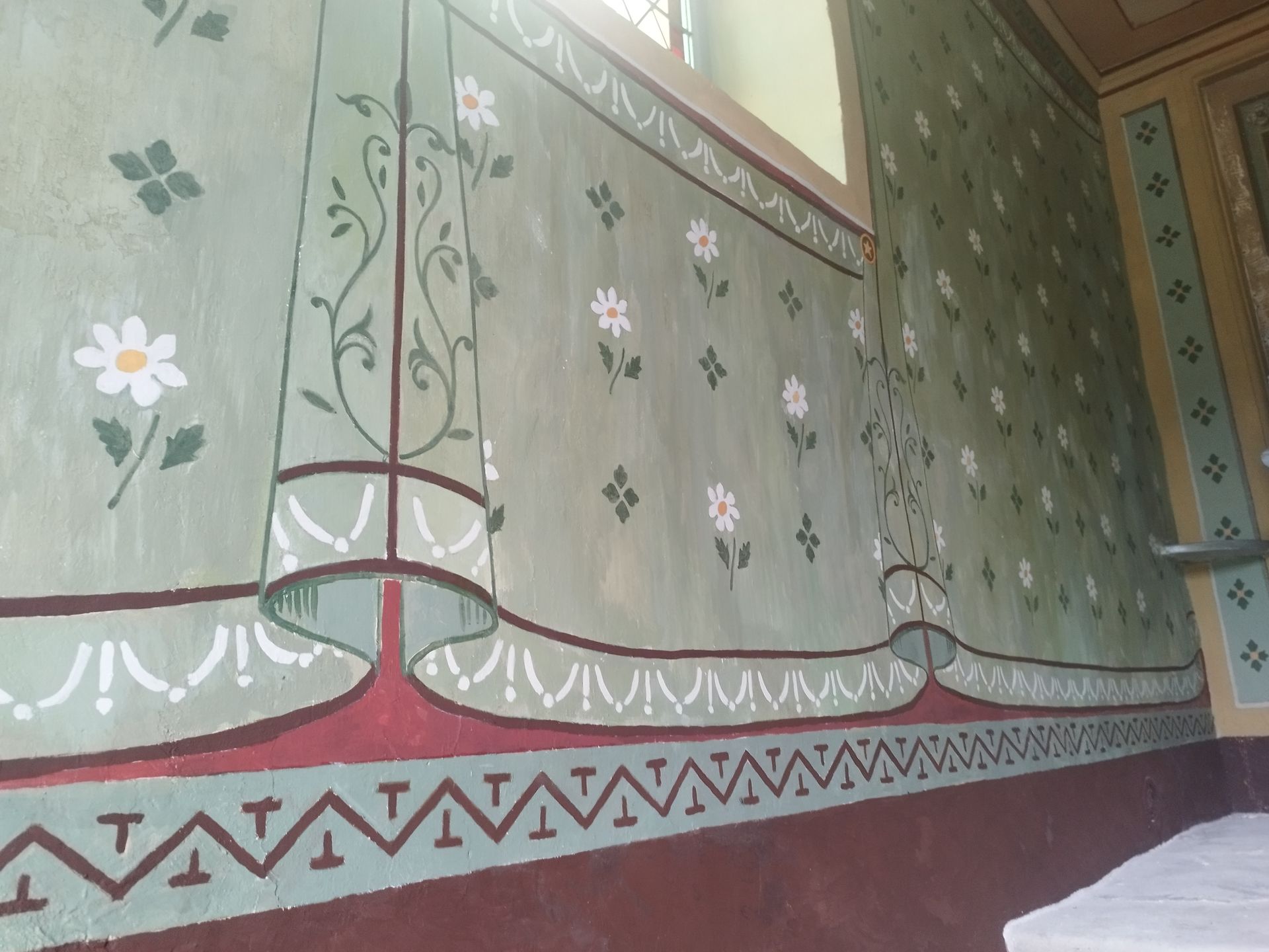 Un mur avec une peinture de fleurs et de feuilles dessus