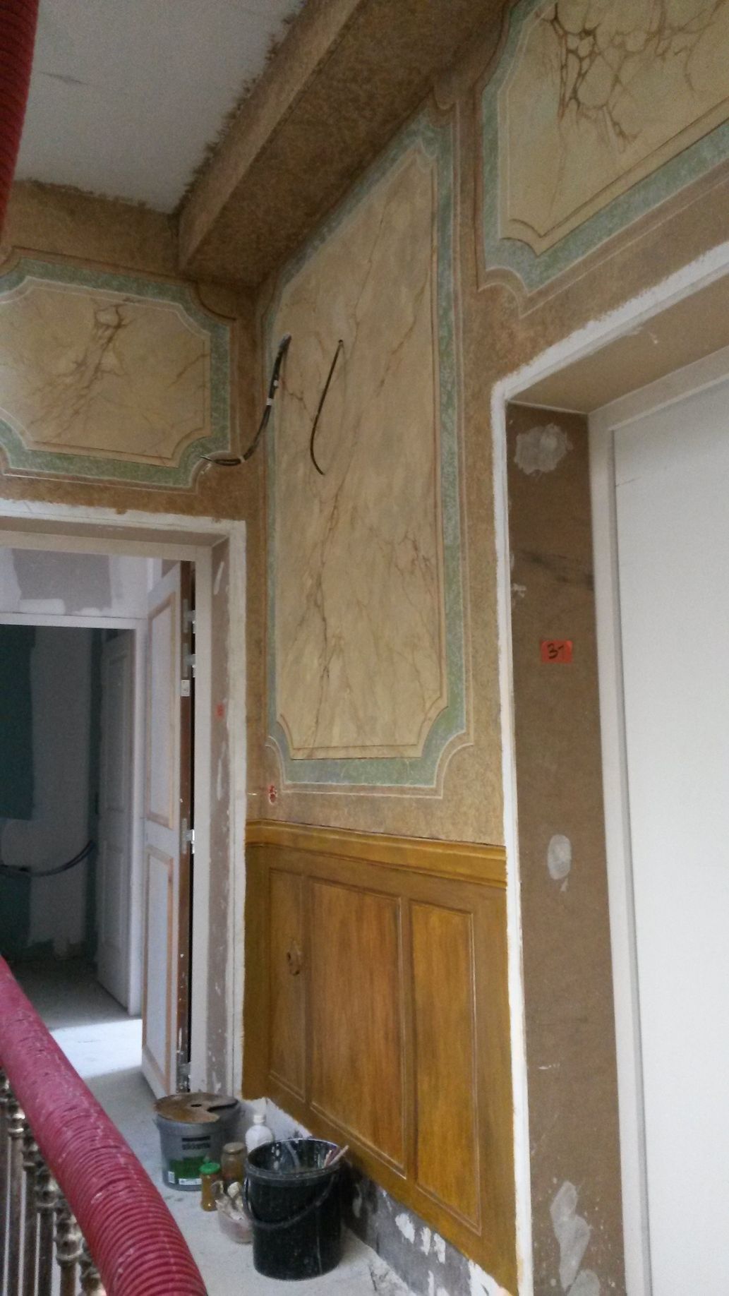 Un couloir avec un escalier menant à une porte et un tableau sur le mur.