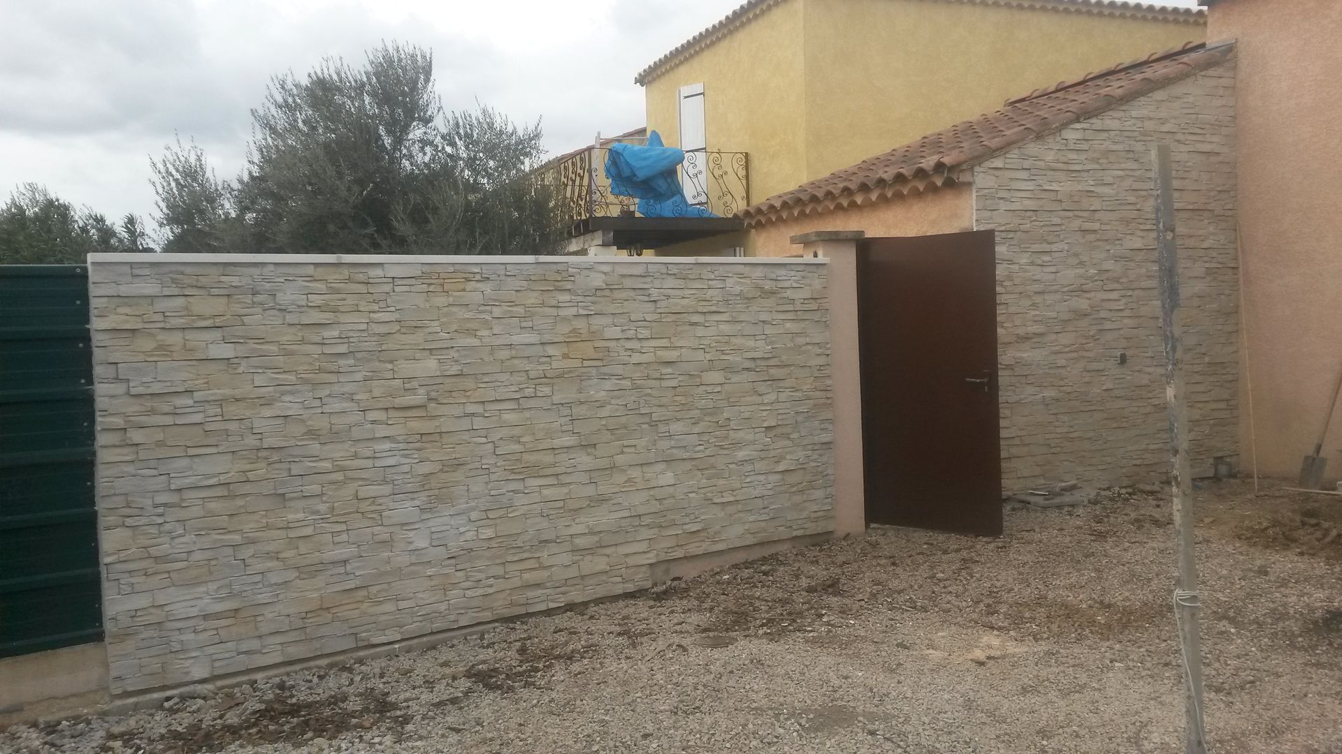 Un mur de briques avec une porte marron devant une maison