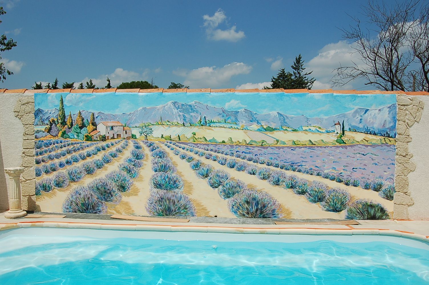 Une piscine avec une peinture de champs de lavande sur le mur