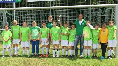 Eine Gruppe junger Jungen posiert vor einem Fußballtor für ein Foto.