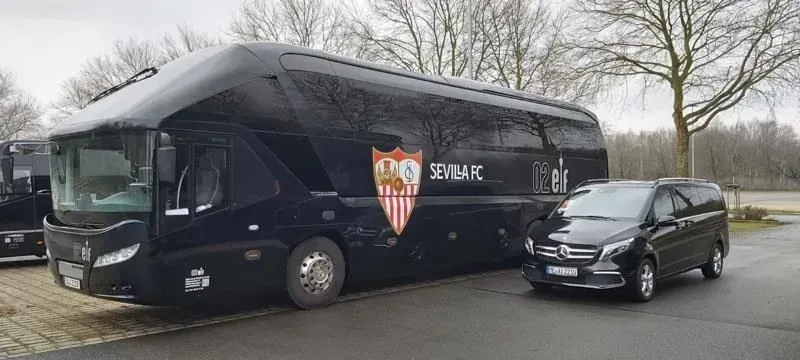 Ein schwarzer Bus und ein schwarzer Lieferwagen stehen nebeneinander auf einem Parkplatz. 02elf Travel GmbH & Co KG