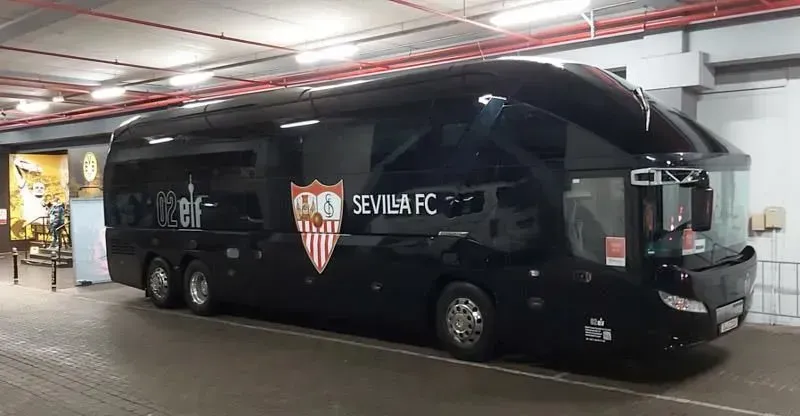 Ein schwarzer Bus mit der Aufschrift „Sevilla FC“ an der Seite steht in einem Parkhaus. 02elf Travel GmbH & Co KG