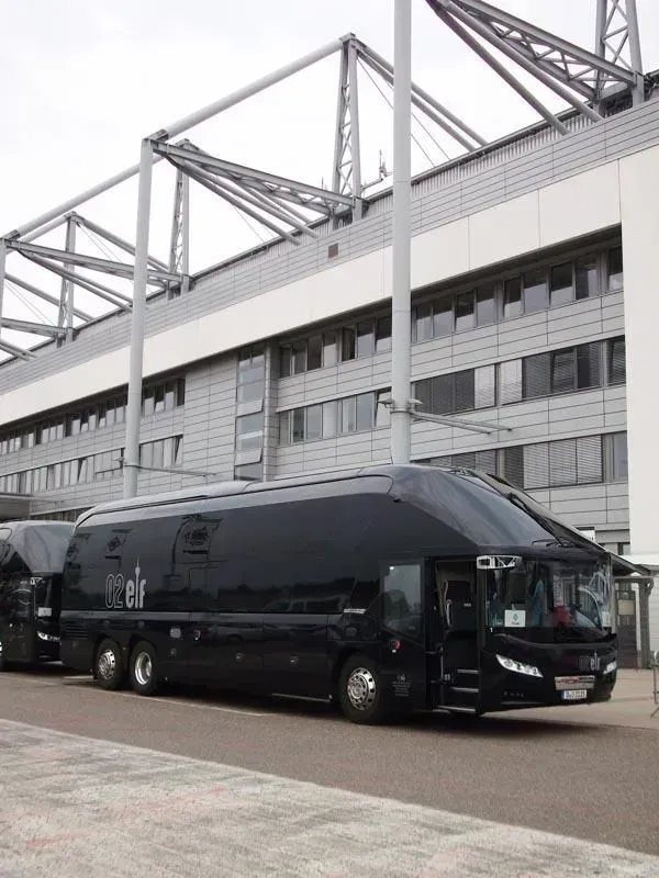 Ein großer schwarzer Bus steht vor einem großen Gebäude, 02elf Travel GmbH & Co KG