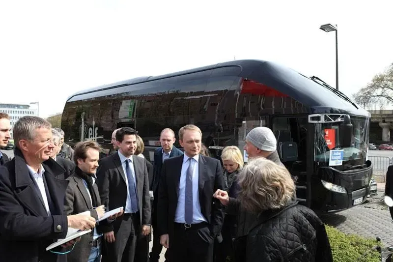 Eine Gruppe von Menschen steht vor einem Bus, darunter Christian Lindner, 02elf Travel GmbH & Co KG