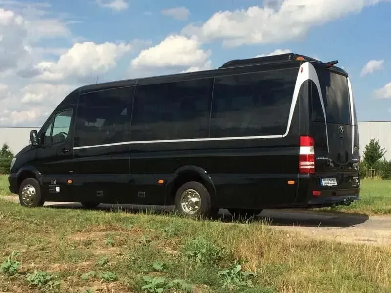 Ein schwarzer Lieferwagen ist auf einer Wiese geparkt. 02elf Travel GmbH & Co KG