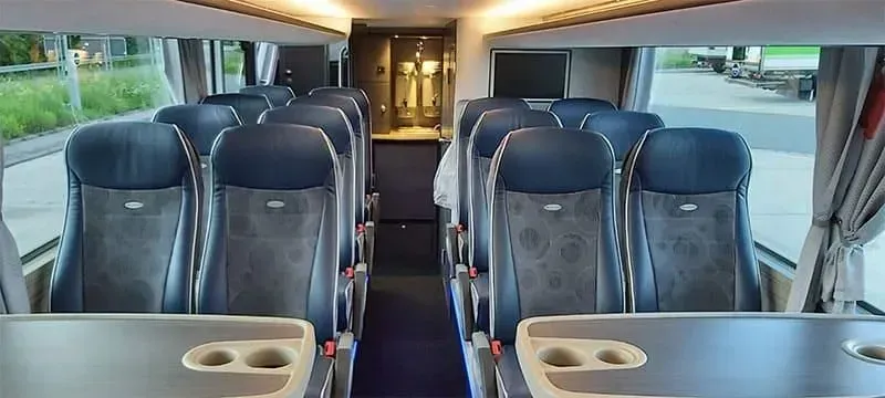 Innenraum eines leeren Reisebusses mit blauen Sitzen und Gang, Blickrichtung Vordertür