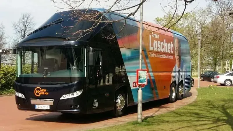 Ein großer Bus mit dem Wort Laschet an der Seite, 02elf Travel GmbH & Co KG