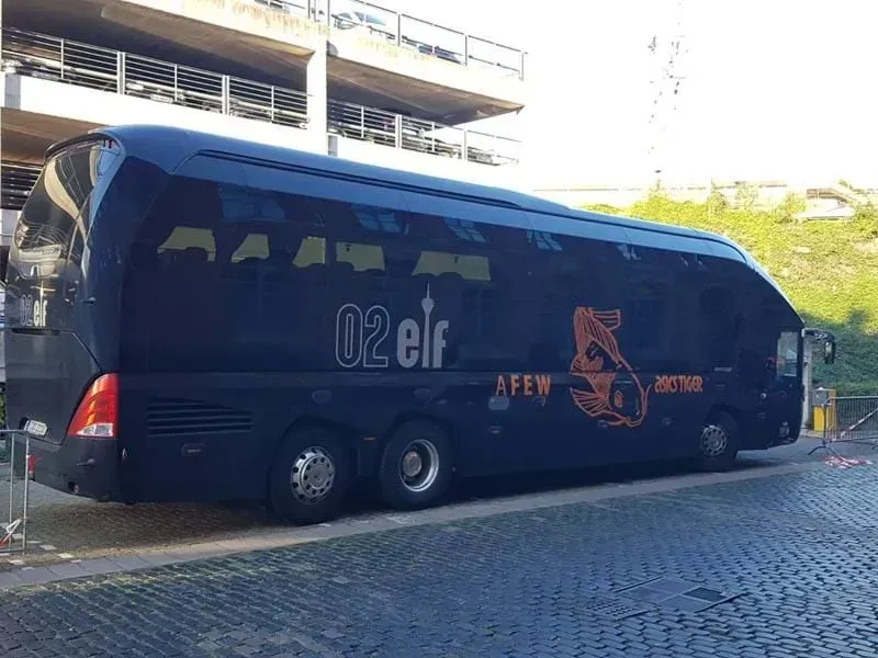 Ein schwarzer Bus parkt auf einer Kopfsteinpflasterstraße. 02elf Travel GmbH & Co KG